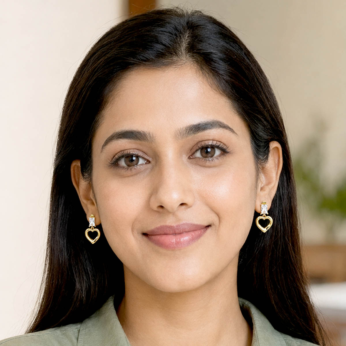 Gold-tone open heart drop earrings with rectangular clear stones on a white background.
